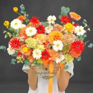 Giỏ hoa chúc mừng công ty tươi tắn với đồng tiền, cúc mẫu đơn, hồng cam, hồng nhạt, lá bạc và eucalyptus.