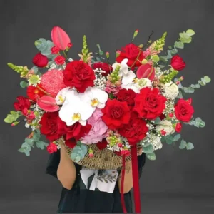 Giỏ hoa tặng sếp nữ sang trọng với hoa hồng đỏ, lan hồ điệp trắng, baby trắng, mẫu đơn và lá bạc.