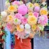 Người giao hoa đang cầm bó hoa rực rỡ với sắc vàng, hồng, trắng tại shop hoa tươi gần chợ