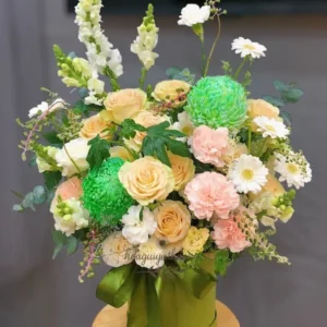 Lẵng hoa sinh nhật tông xanh – vàng nhẹ nhàng gồm hoa hồng, cẩm chướng, pingpong xanh và lá phụ.