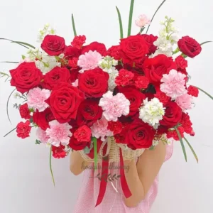 Cô gái ôm bó hoa tươi rực rỡ gồm hoa hồng đỏ và cẩm chướng hồng từ shop hoa đẹp gần đây.