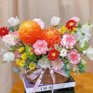 Giỏ hoa sinh nhật mẹ gần đây – phối màu cam rực rỡ và hồng pastel, đặt trên nền khăn trắng nổi bật