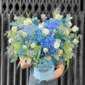 Một người cầm giỏ hoa lớn sắc xanh nổi bật – hình ảnh minh họa cho từ khóa địa chỉ shop hoa gần đây.